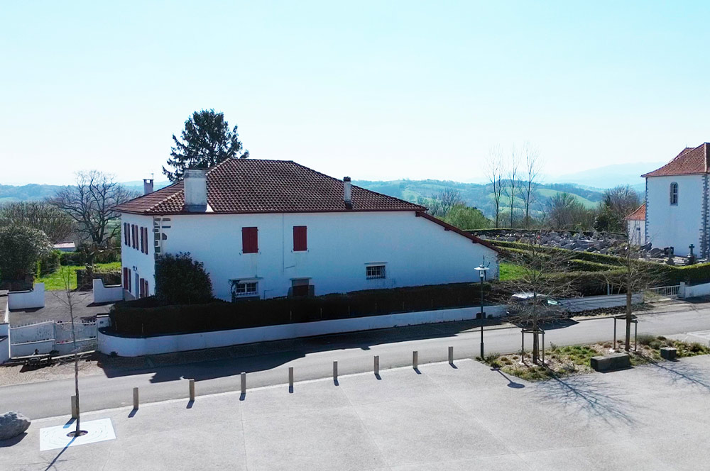La commune de Béhasque-Lapiste vient de lancer un appel à manifestation d'intérêt (AMI) pour la maison Elissetchea, une belle bâtisse traditionnelle basque de 422 m2, acquise par la municipalité et idéalement située en plein centre-bourg, face à la mairie.

Un lieu chargé d'histoire, un avenir à écrire

Ancien bar du village il y a encore quarante ans, la maison Elissetchea a longtemps été le lieu de vie de Béhasque-Lapiste. Aujourd'hui silencieuse, elle attend sa nouvelle vocation. La commune y croit : ce bâtiment peut redevenir le cœur battant du village.

La maison se déploie sur deux niveaux : un rez-de-chaussée de 247 m2 comprenant logement, dépendances, un four à pain, une cave et une grange ; un étage de 175 m2 avec quatre chambres et une salle de bains. Sa position stratégique, entre le fronton, l'église et la mairie, en fait un lieu de passage naturel et de rassemblement évident.

Un projet ouvert, ancré dans l'identité locale

La mairie ne veut pas imposer un concept : elle lance une invitation. Bar, restaurant, hébergements, salle de réception, épicerie en circuit court, services aux habitants, espace culturel... toutes les idées sont les bienvenues, pourvu qu'elles soient viables, ambitieuses et fidèles à l'identité du village.
La commune sera attentive à plusieurs critères : la solidité économique du projet, sa sensibilité écologique, ses liens avec les producteurs et acteurs locaux, et surtout la volonté du ou des porteurs de s'installer durablement dans le village. La proximité du Chemin de Saint-Jacques-de- Compostelle et le développement d'un tourisme diffus dans la région constituent autant d'atouts pour un projet à vocation touristique et de services.
Le montage juridique sera flexible : bail commercial, emphytéotique, convention d'occupation ... afin de faciliter l'installation du futur exploitant.


Derrière ce projet, il y a une équipe. Élue à la tête de la commune, Emmanuel Recalde, nouveau maire de Béhasque-Lapiste, insuffle à sa municipalité une dynamique volontariste et tournée vers l'avenir. Entourée de ses conseillers municipaux, il a fait de la revitalisation du centre-bourg l'une de ses priorités.
« Nous croyons que ce lieu peut devenir le cœur battant de notre village, et nous cherchons la personne ou l'équipe qui partage cette vision »
Une formule qui dit tout de l'esprit dans lequel la nouvelle équipe municipale aborde ce dossier : non pas une procédure administrative froide, mais un appel sincère lancé aux entrepreneurs, artisans, créateurs et familles qui souhaiteraient construire leur vie dans ce coin authentique du Pays basque.

Comment candidater ?

Les visites du site se dérouleront exclusivement du 13 au 24 avril 2026. Les candidats intéressés
sont invités à s'inscrire via le site de la commune : https://behasque-lapiste.fr
Les dossiers de candidature complets devront être transmis par e-mail à contact@mairiebehasquelapiste.fr avant le 20 mai 2026. 

Le dossier de candidature et le règlement de l'AMI sont téléchargeables directement sur le site.
Pour tout renseignement, la mairie est joignable au 05 59 65 80 27, aux heures d'ouverture habituelles (lundi 13h30–18h, jeudi 9h–12h et 13h30–18h, vendredi 15h–18h30).